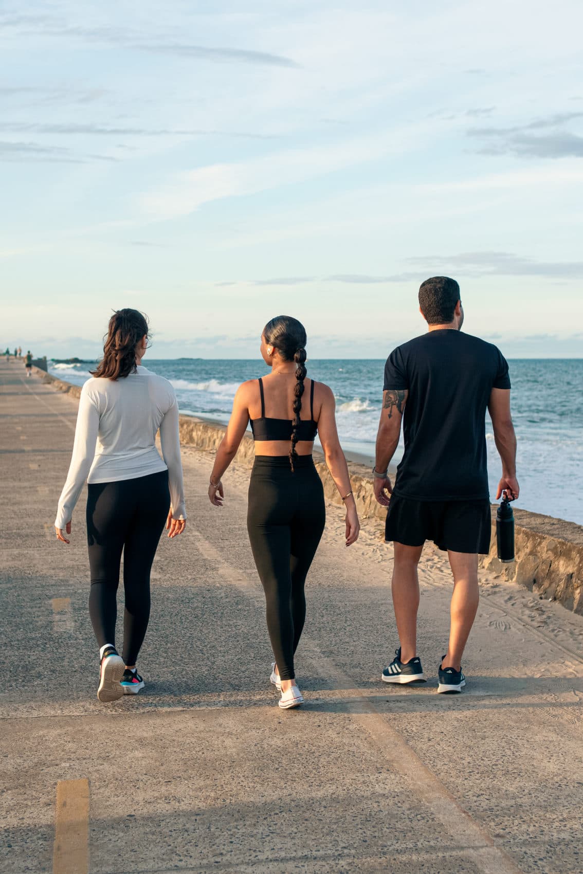 Três pessoas caminhando juntas pelo píer